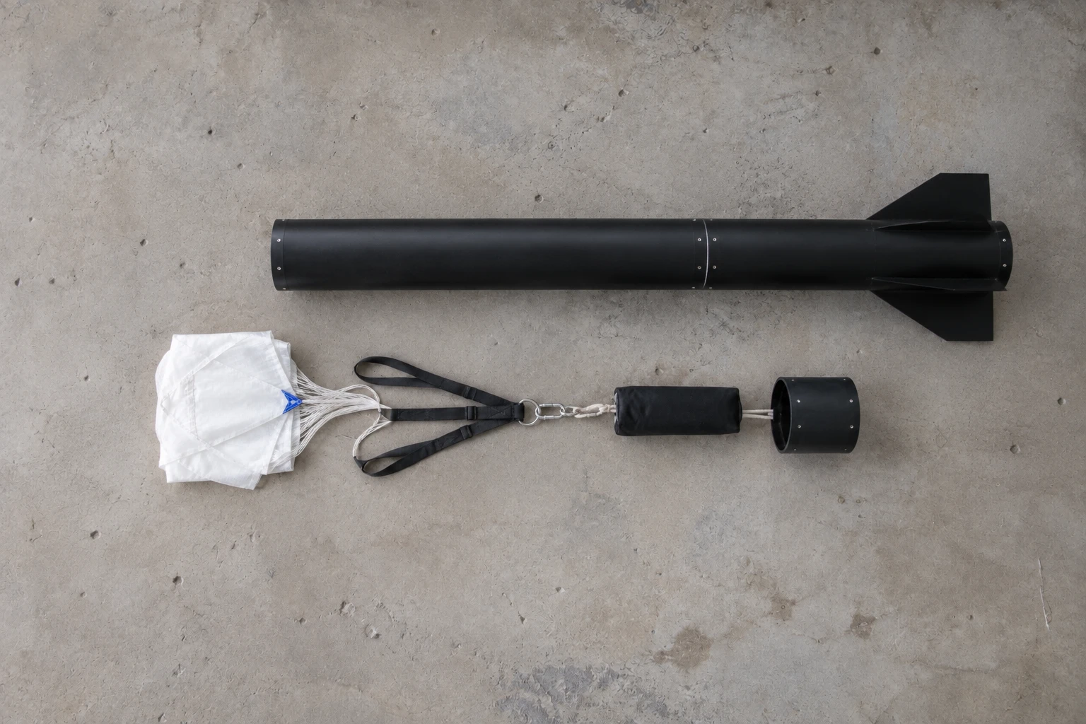 The parachute, harness and attachment hardware laid out beside the recovery bay